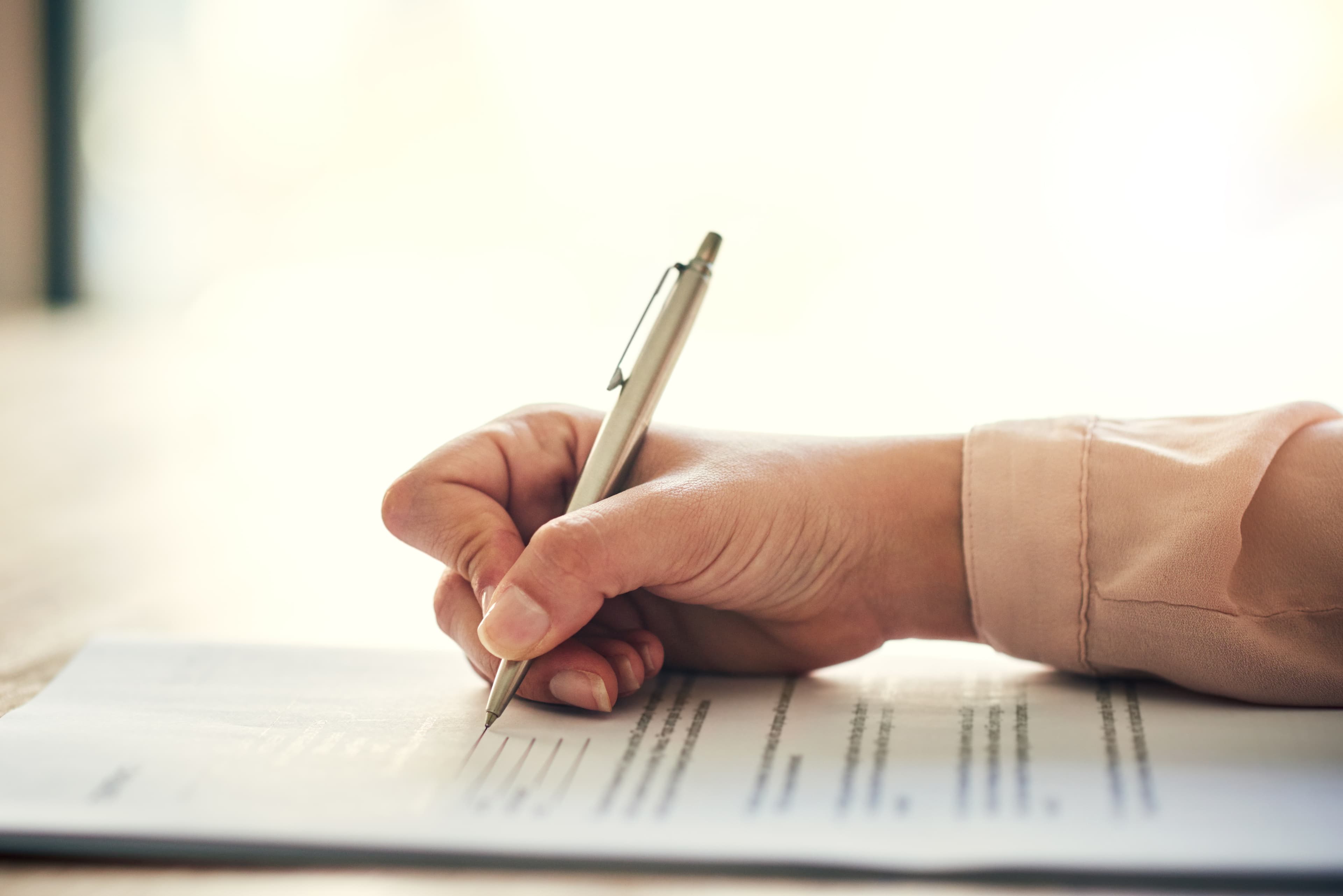 Woman filling out a form with a metal pen