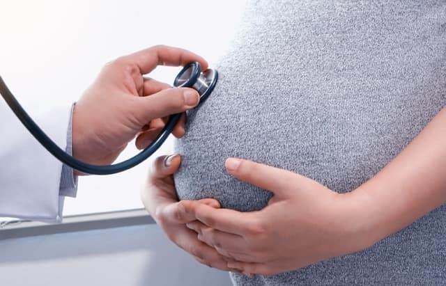 pregnant woman getting. check up in a gray dress